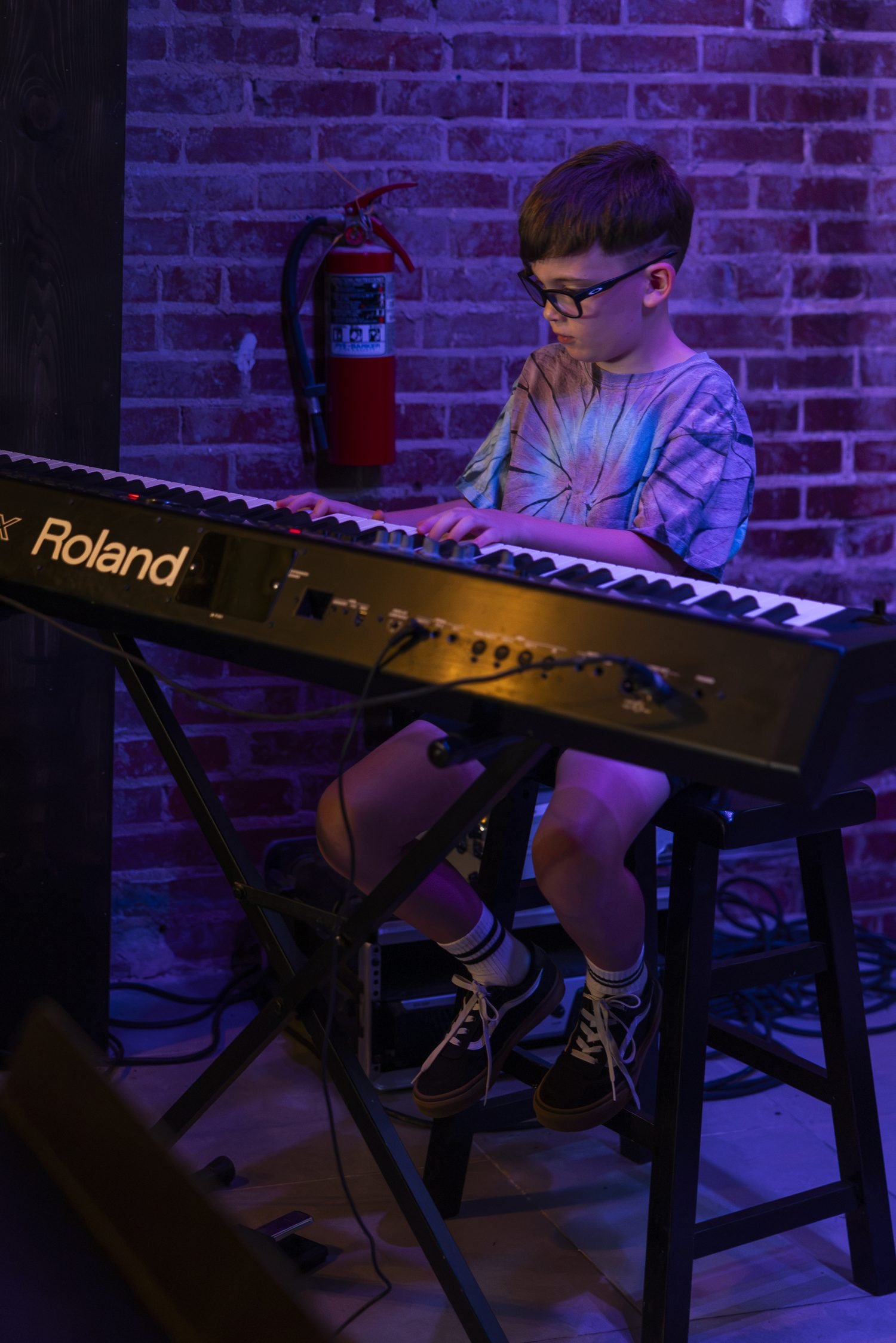 A young pianist playing a Roland keyboard against the brick wall at Lo-Fi Coffee Bar