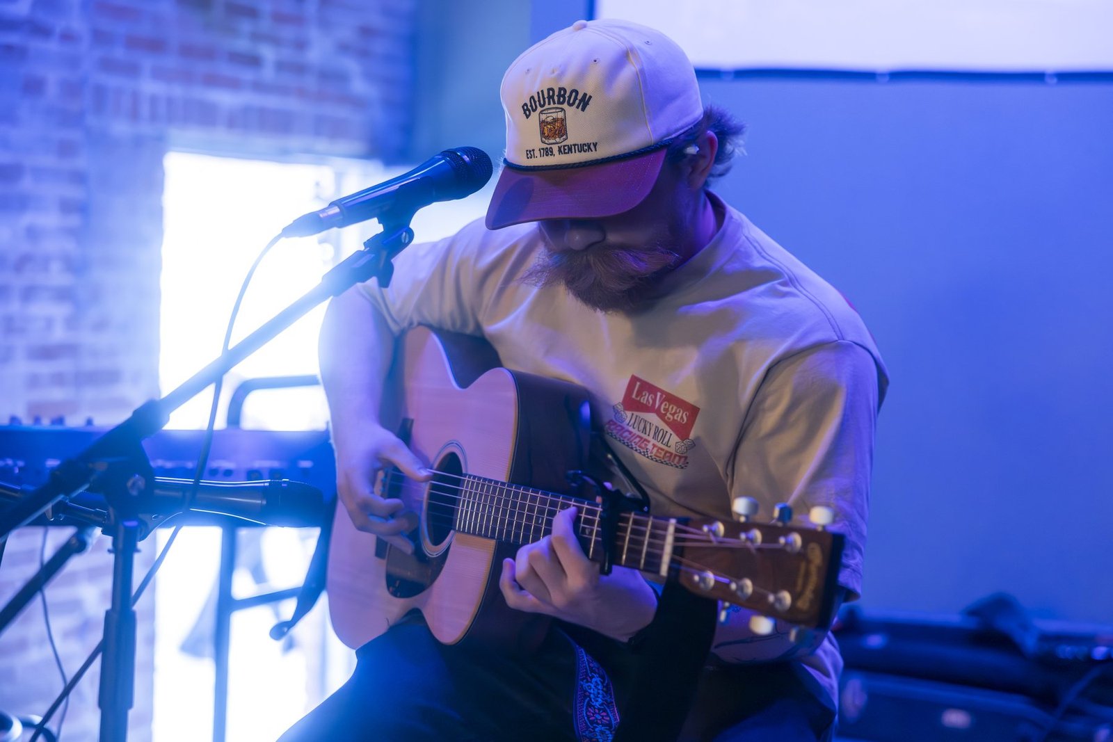 Ethan Carroll playing acoustic guitar at a Ghost Noise open mic night